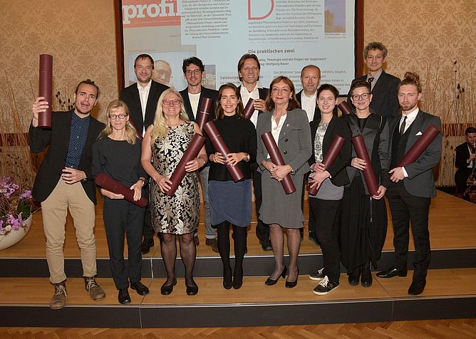 Gruppenfoto der Absolvent*innen mit Urkundenrollen