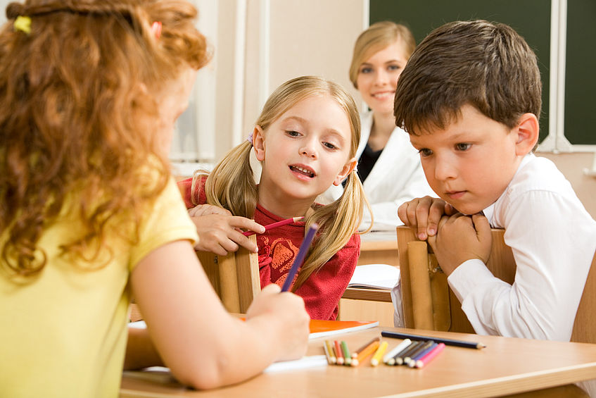 Kinder sehen einem Mädchen mit Stift zu